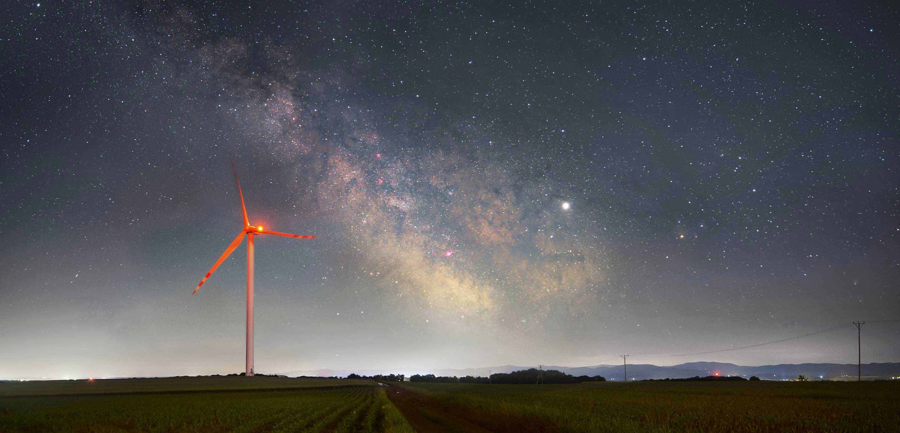 A wind turbine illuminated against the night sky, harnessing renewable energy in the darkness. A wind turbine illuminated against the night sky, harnessing renewable energy in the darkness.